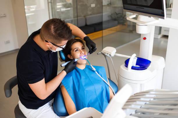 a dentist carefully applying a composite filling to a patient’s tooth.